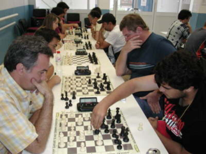 Jugadores en un torneo de ajedrez, concentrados en sus partidas en una sala bien iluminada.
