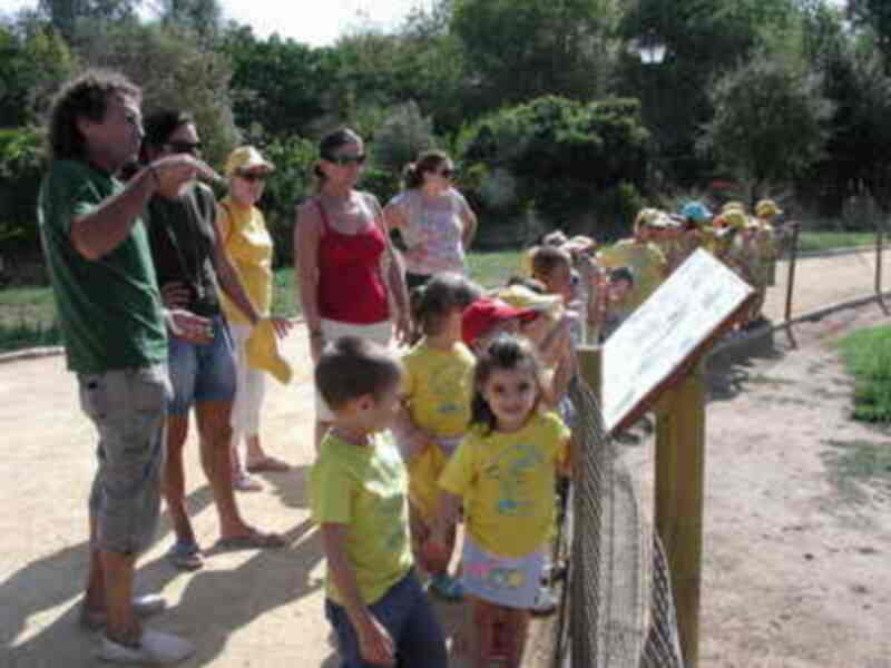 Una familia disfruta de una visita guiada en un parque, aprendiendo sobre la naturaleza al lado de un panel informativo.