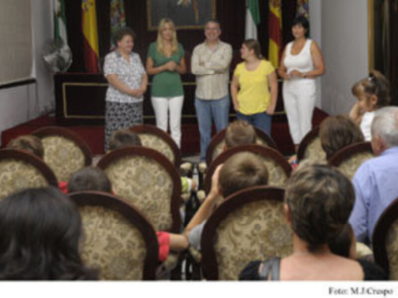 Una reunión de trabajo en una sala con sillas tapizadas y banderas en el fondo.