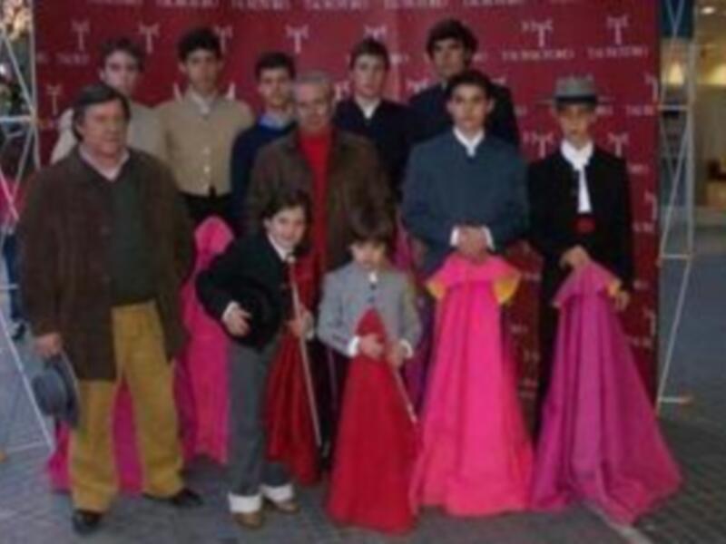 Una familia feliz en trajes tradicionales de España, posando frente a un póster de la marca Tintoretto.