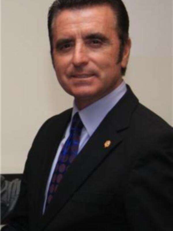 Un hombre en traje y corbata, posando frente a un fondo neutro.