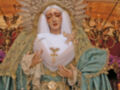 Estatua religiosa de una virgen con vestimenta tradicional, corona y guantes blancos.