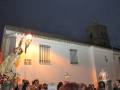 Procesión religiosa en una iglesia con una imagen de la Virgen en el centro, bajo un cielo nocturno.