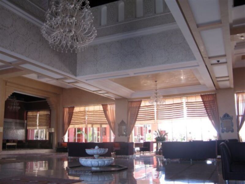 Salón con techo decorado, mesa de centro y sillas.