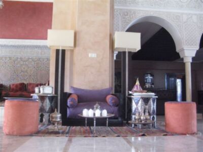 Interior de un hotel con decoración marroquí, muebles de estilo tradicional y detalles geométricos en la pared.
