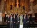 Grupo de personas posando en una iglesia con una imagen religiosa en el fondo.