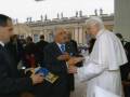 El Papa intercambia saludos con un dignatario en un evento formal, con el Palacio Apostólico de San Pedro en el fondo.