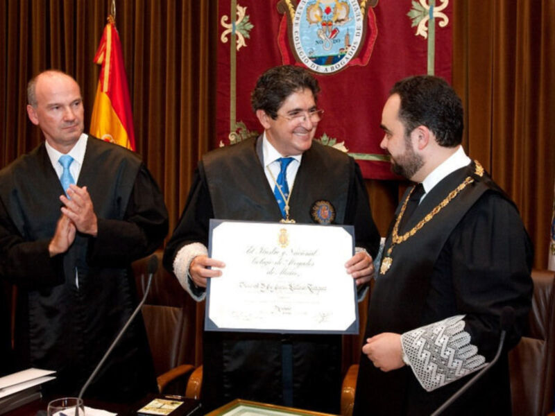 Entrega de un certificado en una ceremonia oficial con uniformes judiciales y banderas.