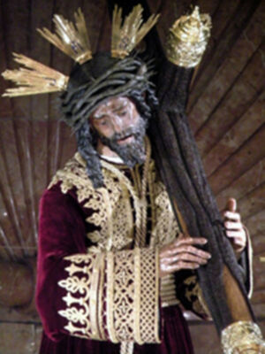 Representación escultórica de Jesús Nazareno con corona de espinas y manto dorado, en un entorno de madera.