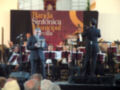 Concierto de la Banda Sinfónica Municipal de Sevilla en un escenario con músicos interpretando y un conductor dirigiendo.