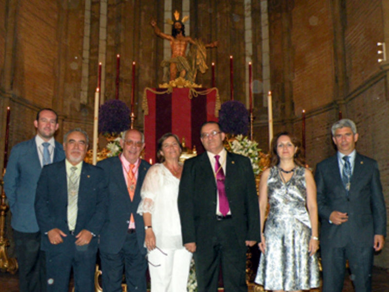 Grup de persones en una cerimònia religiosa davant d'un retaule amb la imatge del Crist.