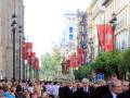 Procesión religiosa con estandartes y estatuas procesionales en una calle de Sevilla.