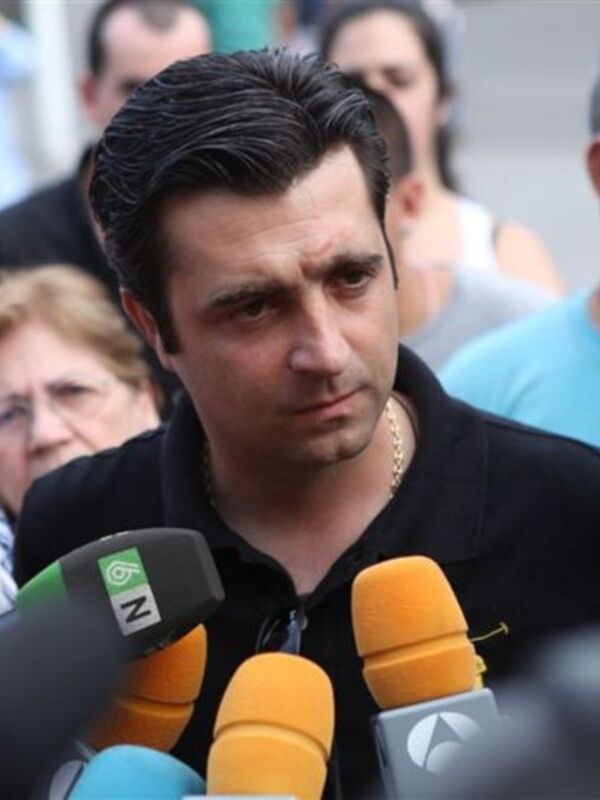 Un hombre con una peluca negra y micrófonos en una conferencia de prensa.