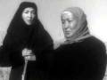 Dos mujeres en una imagen antigua, posiblemente de una familia o generación, con vestimenta tradicional y un fondo sencillo.