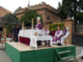 Eucaristía en una iglesia con sacerdotes vestidos de color morado y blanco, altar cubierto con mantel blanco y velas encendidas.