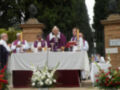 Una imagen de una ceremonia religiosa en un jardín, con sacerdotes vestidos con hábitos y una mesa con flores y velas.