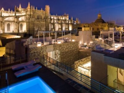 Catedral de Sevilla en la noche, con una piscina y terrazas iluminadas.