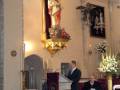 Interior de una iglesia con un altar dorado y un sacerdote oficiando una ceremonia.