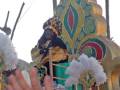 Un carnaval con una figura de madera en un carro festivo, rodeada por flores y decoraciones.