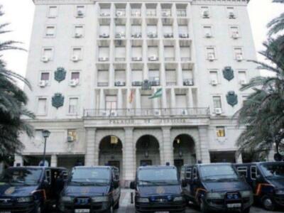Edificio administrativo con varios vehículos estacionados en la entrada.