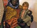 Un niño se abraza con un personaje de la tradición navideña, posiblemente un personaje de la noche de los tres reyes magos, en un contexto cultural o museográfico.