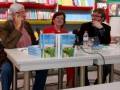 Tres personas en una mesa de libros, discutiendo sobre 'Al Mizan' en una librería.