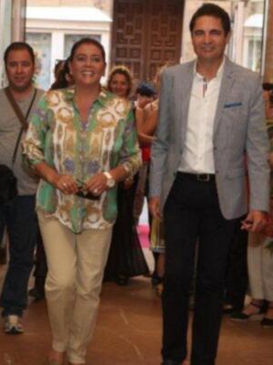 Personas en un evento formal, con una mujer en el centro luciendo un vestido floral y pantalones beige.