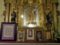 Altar con estatuas religiosas, una imagen de la Virgen y flores.