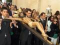 Una procesión religiosa con una figura de Cristo crucificado siendo llevada por un grupo de personas vestidas formalmente.