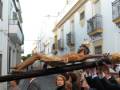 Imagen de una procesión religiosa con una figura de Jesús crucificado siendo portada por personas en un ambiente urbano.