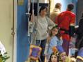 Un grupo de niños disfrazados, posiblemente como los Reyes Magos, están en una escena que parece ser un hospital. Algunos niños llevan trajes de color brillante y sombreros, mientras que otro niño tiene un hospitalizador en su mano. La imagen sugiere una celebración o evento festivo que se está llevando a cabo en un entorno médico.