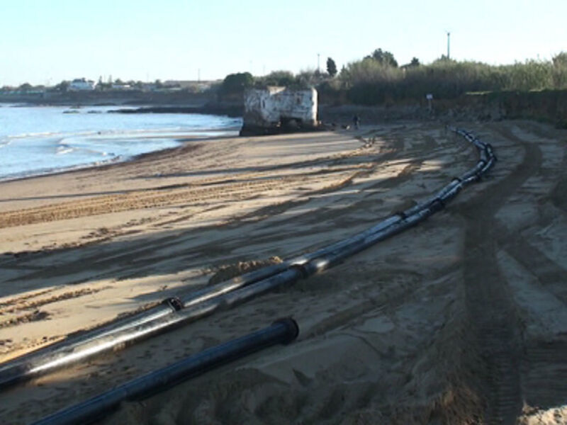 Pista de carreras de motocross en la playa, con tubos de metal y arena alrededor.