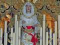 Imagen de una Virgen María vestida con un manto blanco y un cetro, rodeada por palmas doradas.
