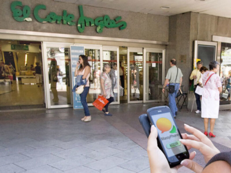 Persona usando un teléfono inteligente frente a la entrada de un centro comercial.