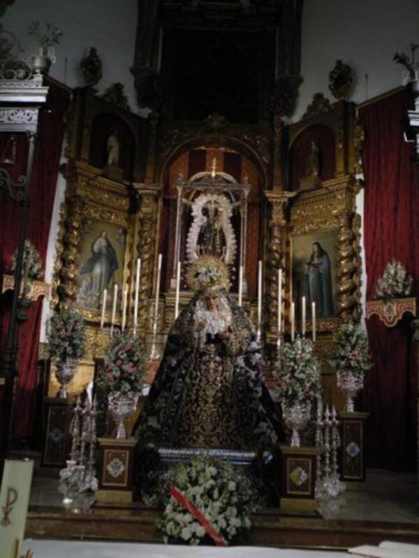 Interior de una iglesia con altares ornamentados, estatuas religiosas y flores.