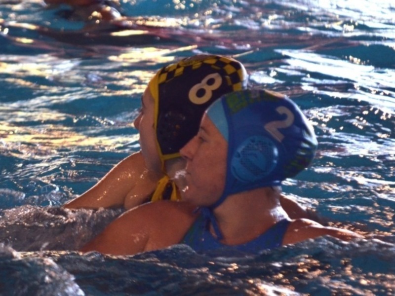 Jugadores de waterpolo en acción durante un partido en una piscina.