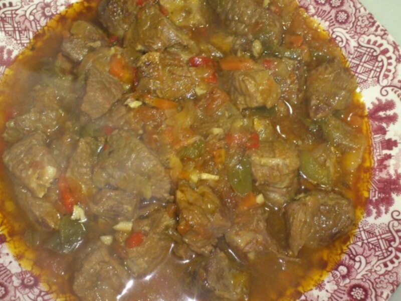 Un delicioso guiso de carne con verduras y especias, servido en una placa decorada.