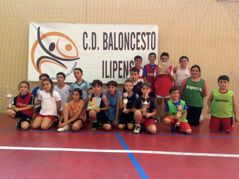 Equipo de baloncesto infantil posando con trofeos en una cancha deportiva.