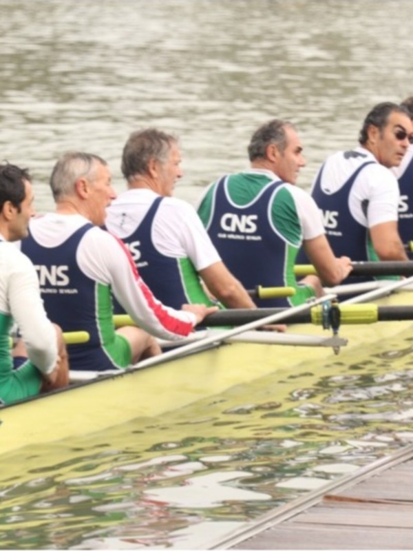 Equipo de remo en barca de competición, uniformes de CNS, listos para la acción en el agua.