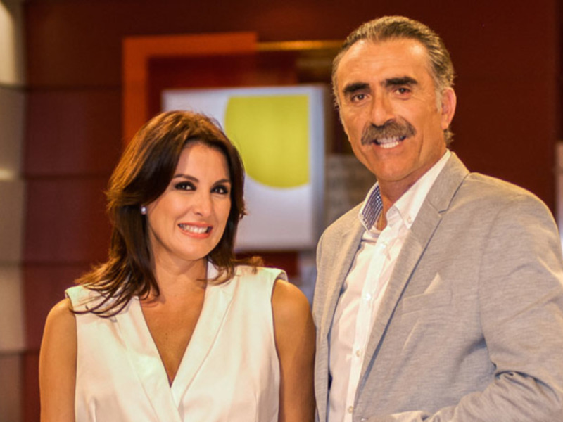 Dos personas sonrientes en un entorno profesional, posiblemente en una entrevista o presentación.