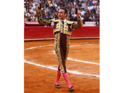 Un torero celebra en el ruedo tras una actuación exitosa, rodeado por un público entusiasmado.