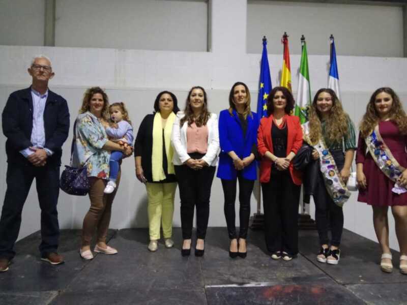 Una familia y amigos posan frente a una pared blanca con banderas de diferentes países. La imagen muestra un ambiente festivo o formal, posiblemente en una celebración o evento.