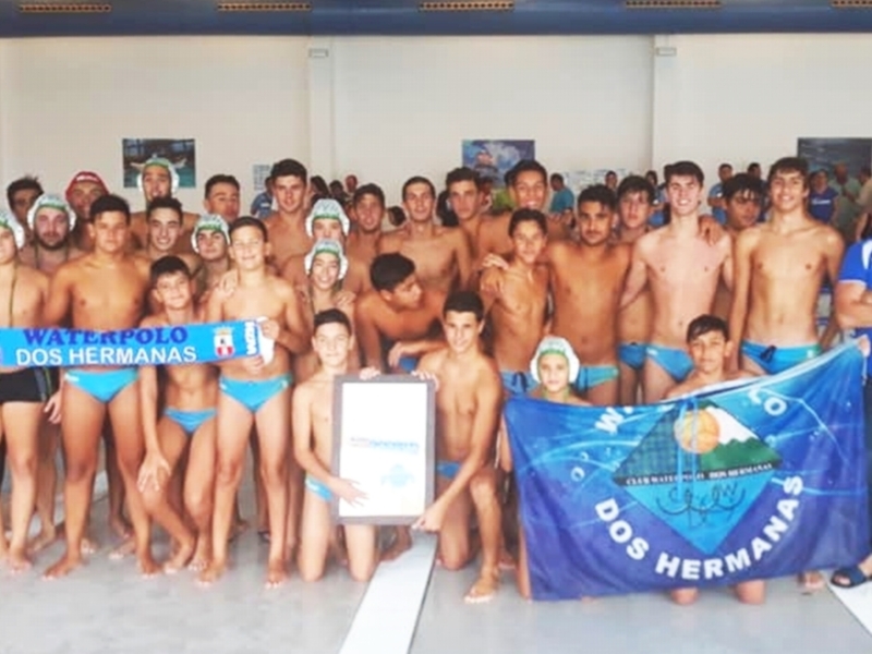 Equipo de natación masculina posando con un trofeo y una bandera en una piscina.