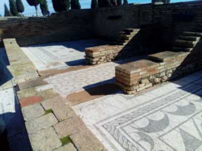Un antiguo mosaico de piedra en una estructura de ladrillo, con patrones geométricos y vegetales.