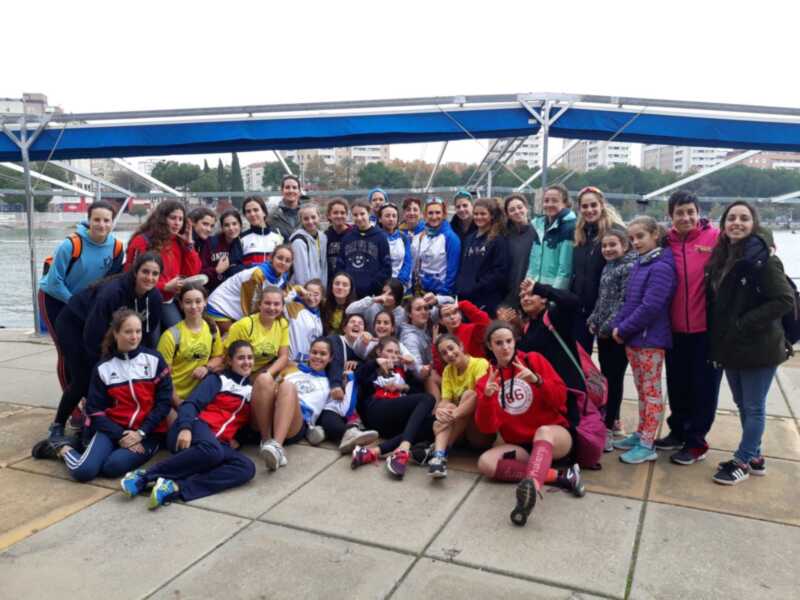 Grupo de jóvenes posando en la orilla del río con un toldo azul al fondo.