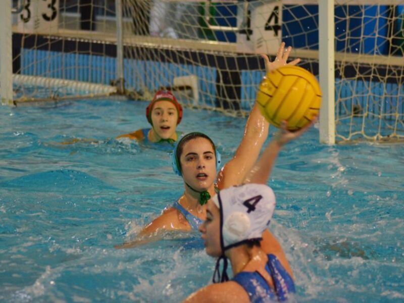 Jugadores de waterpolo en acción, con un portero y dos jugadores en el agua. El objetivo es marcar goles al contrario equipo.