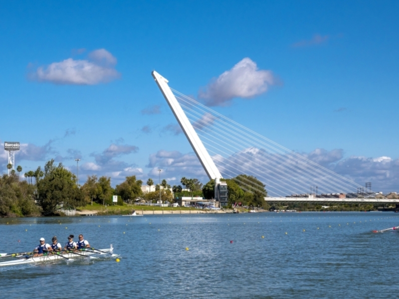 Equipo de remo en acción bajo el Puente de la Barqueta, Sevilla, España.