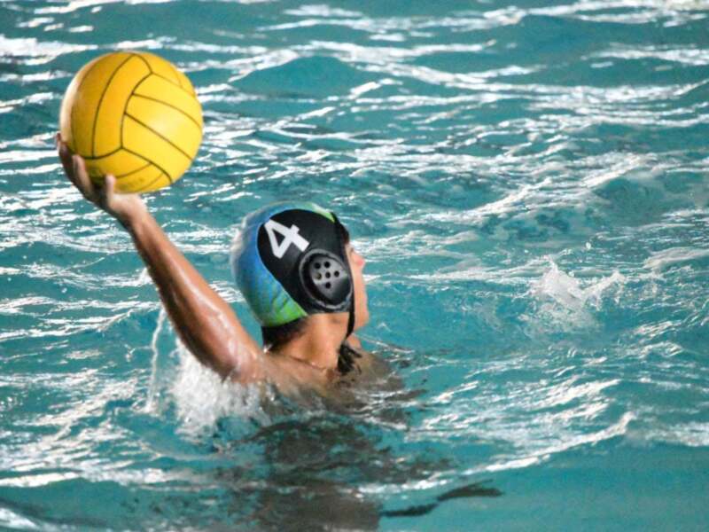 Jugador de waterpolo en acción, sujetando el balón en el agua.