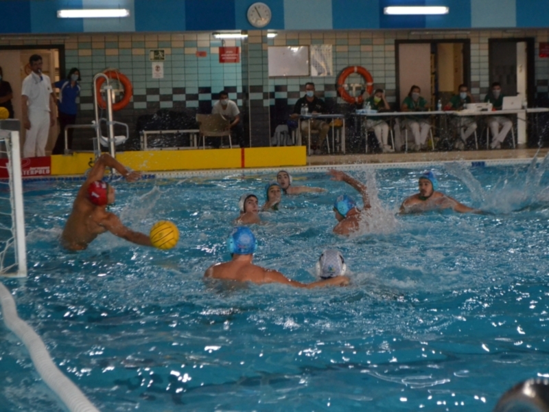 Jugadores de waterpolo en acción durante un partido en una piscina cubierta.