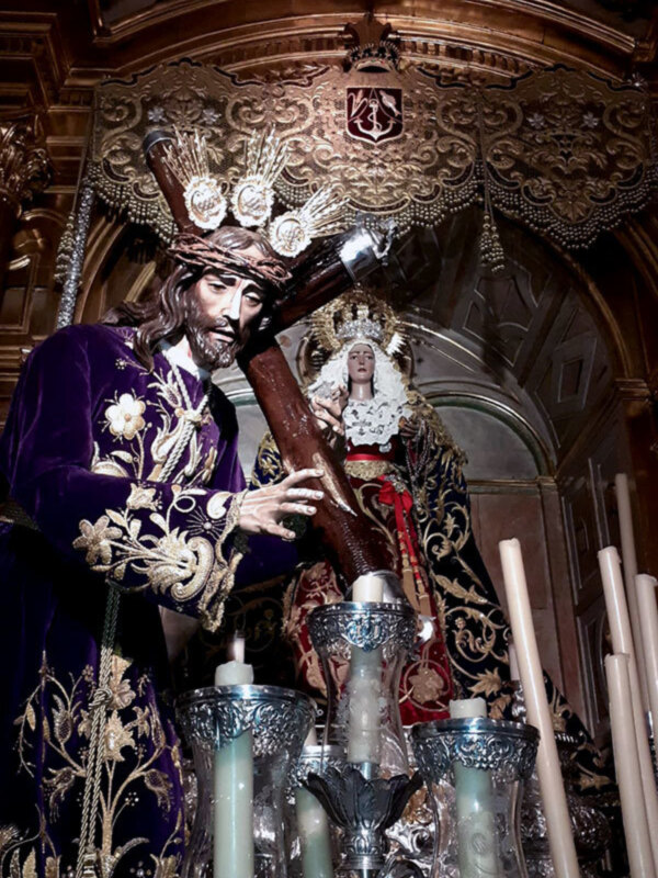 Estatua de Cristo en la iglesia, rodeada de velas y adornos dorados.